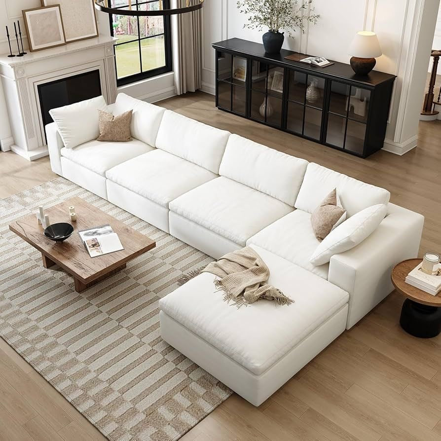 Spacious living room featuring a white sectional sofa with chaise, wood coffee table, and neutral deco